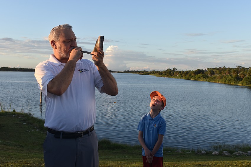 Rabbi Michael Shefrin sounds a Shofar, a rams horn to awaken and stir souls, while his son Jacob called out the sounds.