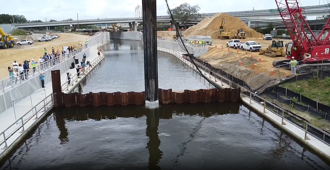 A crane lifts the dam to open the flow of McCoys Creek into the St. Johns River on the Downtown Northbank. The creek will flow between the One Riverside development and the Acosta Bridge. Pedestrians will be able to cross the creek via a bridge on the Riverwalk.