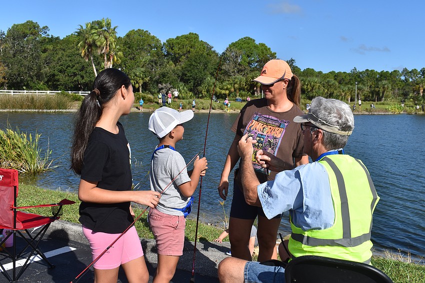 After Lakewood Ranch's Alessia Affinito, 11, and Luca Affinito, 7, get their fishing lines tangled together, mom Valerie Affinito seeks help from volunteer Allen Pfaadt.