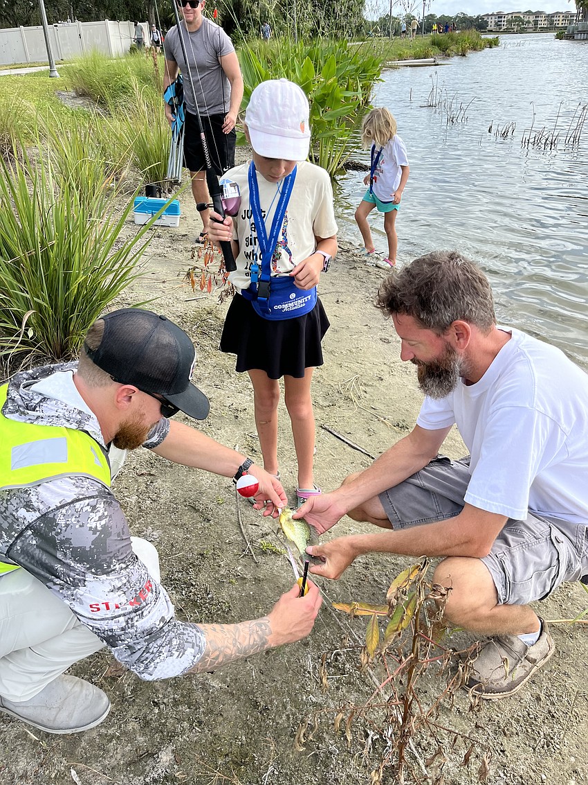 Jordan Grabski, a volunteer ranger provided by Premier Tackle, measures a bluegill that 8-year-old Irelynn Denike caught just before the final whistle blew. Denike is with her dad Rick Denike (on the right).