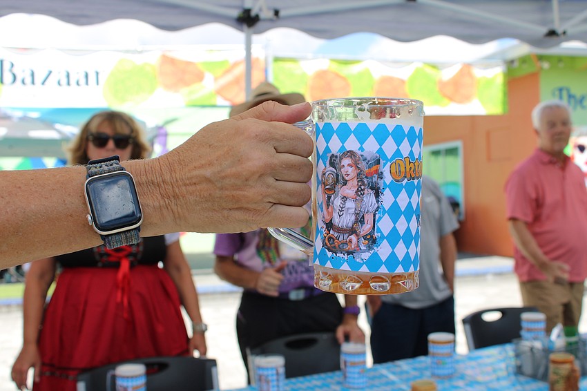Kim Livengood, owner of The Bazaar on Apricot & Lime, shows contestants in the stein-holding competition how they must hold the glass level, without wobbling, to avoid elimination.
