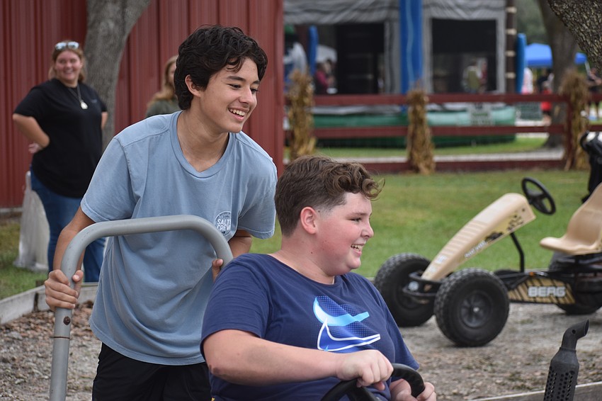 Stuart's Karlo Ochoa pushes Okeechobee's Skylar Banville, both 13, through the race track.