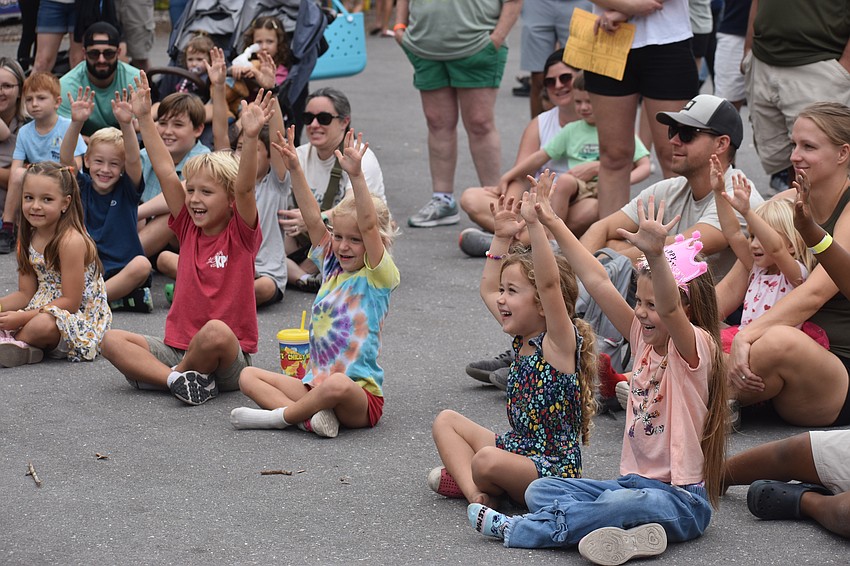 Carter snell, Aubrey Snell, Joni Palmer and Averie Lavoie raise two hands in the air in order to volunteer to be part of Bruce Sarafian's show.