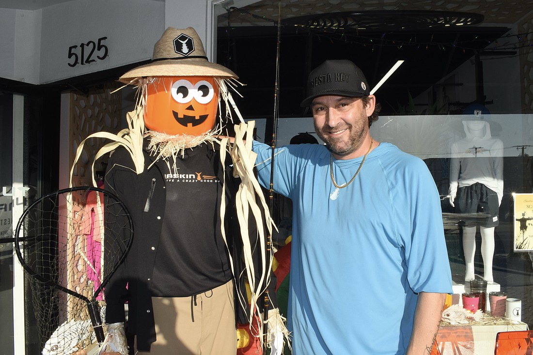 Jonny Chartrand of Tunaskin Aquatic Apparel poses with the shop's scarecrow.