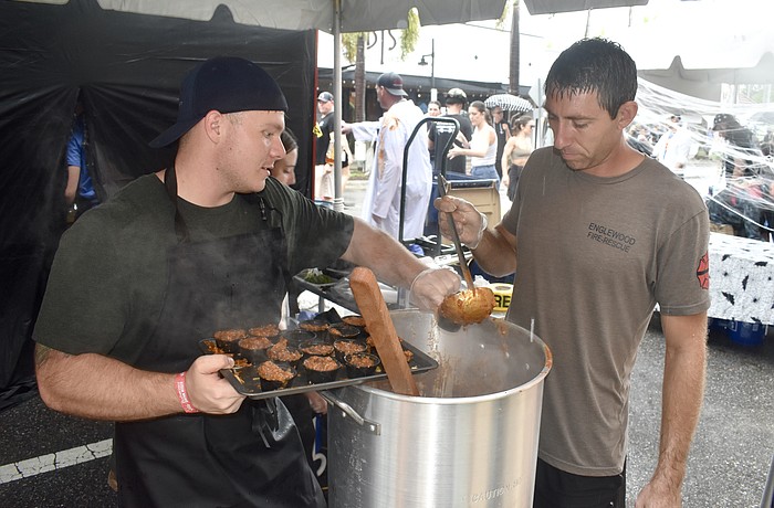 Englewood firefighters Mason Adkins and James Farley prepare cups of chili in 2024.