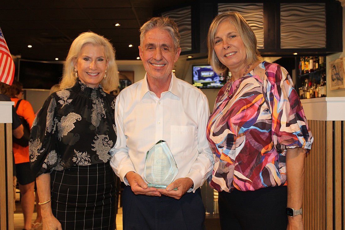 New Kiwanis Club of Longboat Key president Danielle Gladding presents former president Michael Garey, accompanied by his wife, Catherine, with an award for his years of service to the community.