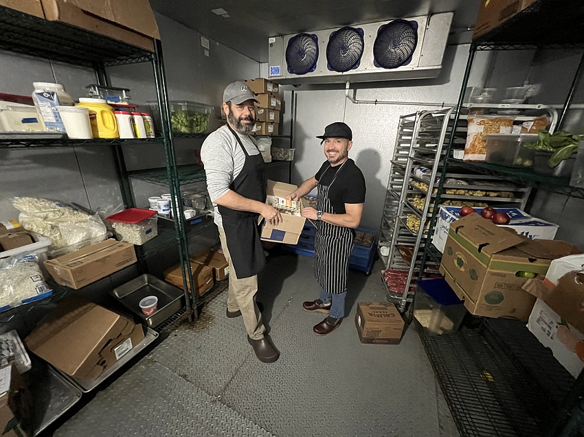 Jonathan Insetta, left, and partner Michael McKinney inside the food storage facility at Bellwether, their restaurant in Downtown Jacksonville.  Insetta said food costs have risen about 30% over the past four years.