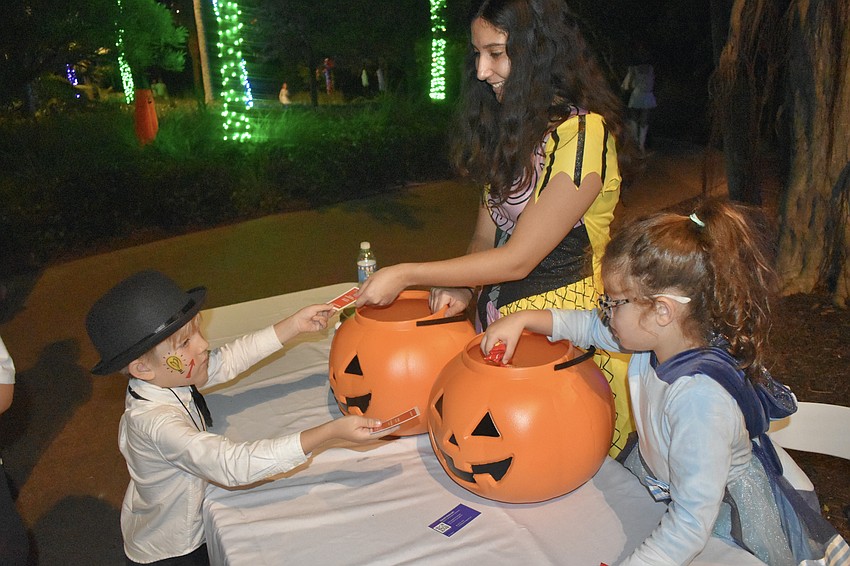 Sebastian Aust, 6, dressed as Mr. Monopoly, hands out Monopoly cards to Joyce Serrano and Ava Callejas, 6.