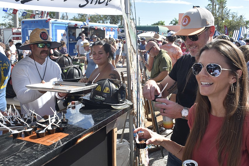 David Truran of North Port Station 85 and Noël Freudenberg offer chili to Brandon English and his wife Jennifer English.