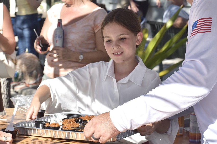 Ellie Bowlin, 9, sets down a tray of chili at the Longboat Key Fire Rescue's tent.