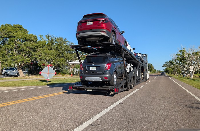A car carrier sits in the median of Gulf of Mexico Drive Tuesday, Oct. 14. Many seasonal residents fly down and have their cars shipped on carriers to Longboat Key, and the return of the car transporters has become known as one of the first signs of the more busy winter season.