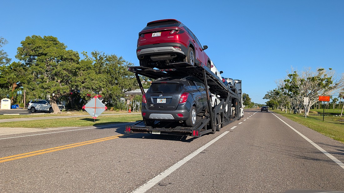 A car carrier sits in the median of Gulf of Mexico Drive Tuesday, Oct. 14. Many seasonal residents fly down and have their cars shipped on carriers to Longboat Key, and the return of the car transporters has become known as one of the first signs of the more busy winter season.