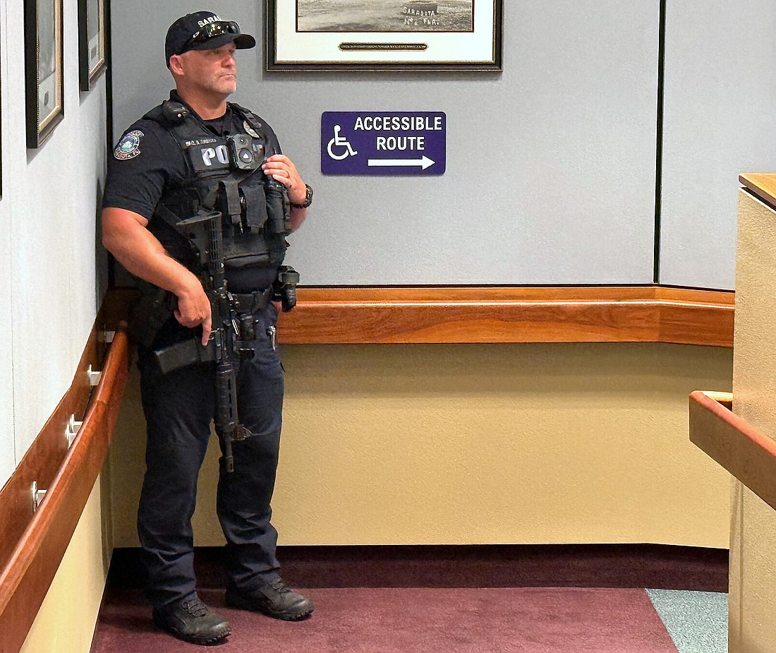A Sarasota Police Department officer armed with a long gun is now stationed in the meeting chamber during City Commission meetings.