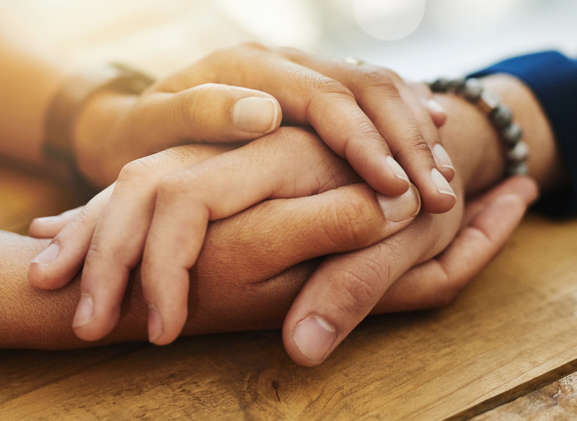 Holding hands, mockup and closeup with trust, solidarity and community on a home table. Therapy, care and gratitude of friends together with hope, respect and love for grief empathy and forgive.