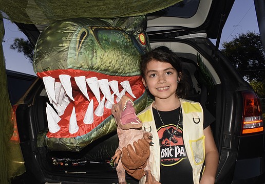 At one of two "Jurassic Park" trunks, Ayla Puccio, 8, helped offer the chance to pet a dinosaur using puppets.