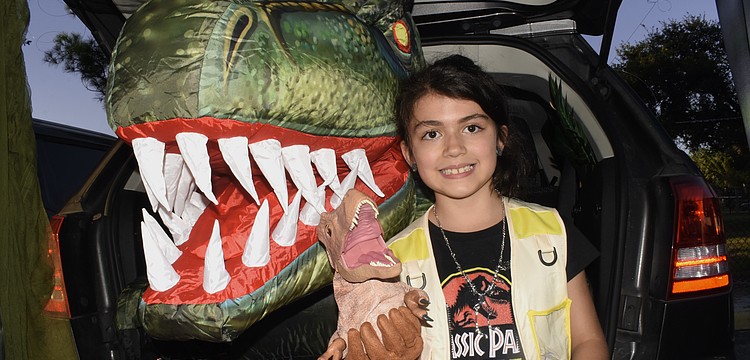 At one of two "Jurassic Park" trunks, Ayla Puccio, 8, helped offer the chance to pet a dinosaur using puppets.