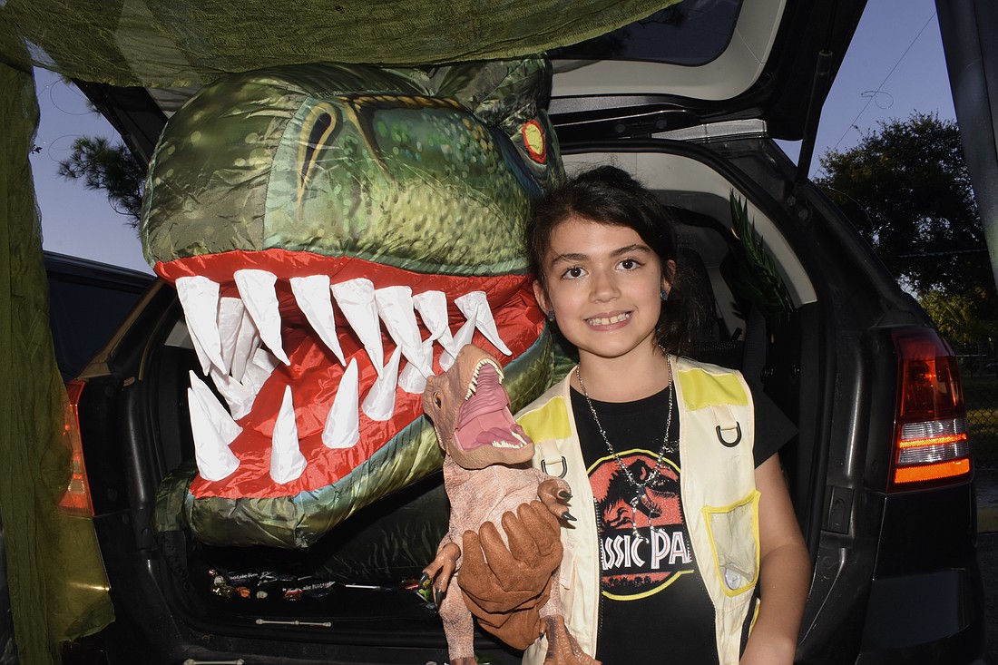 At one of two "Jurassic Park" trunks, Ayla Puccio, 8, helped offer the chance to pet a dinosaur using puppets.