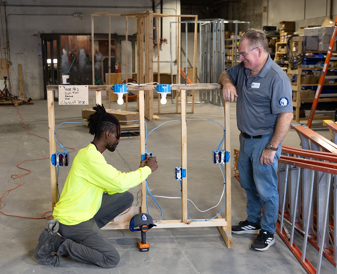 Ishmeal Malachi Robinson Anderson practices branch rough-in, including installation of outlets and lighting circuits, under the guidance of apprenticeship instructor Timothy Townsend Smith.