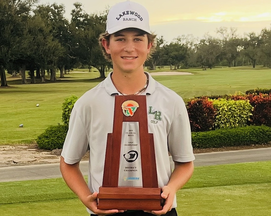 Donovan Plakyda poses for a photo on Oct. 27 with the FHSAA Class 3A District 11 trophy. The junior has dropped 14 strokes in an 18-hole format since his freshman season.