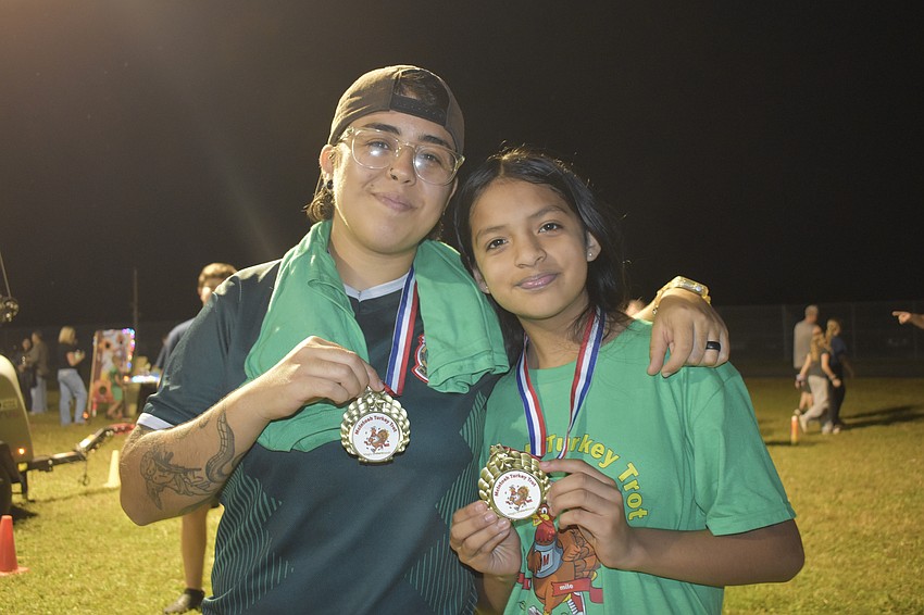 Rubi Barajas holds a Turkey Trot medal alongside daughter Sophia Sanchez, 11.