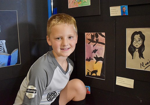 Evan Prince, a second grader at Freedom Elementary, poses next to his masterpiece, "Warm Colored Sky."