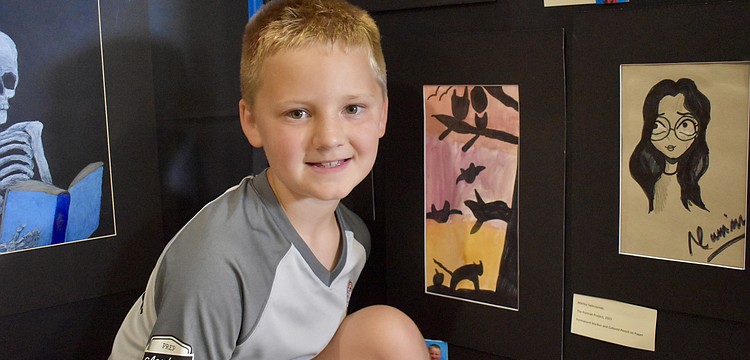 Evan Prince, a second grader at Freedom Elementary, poses next to his masterpiece, "Warm Colored Sky."
