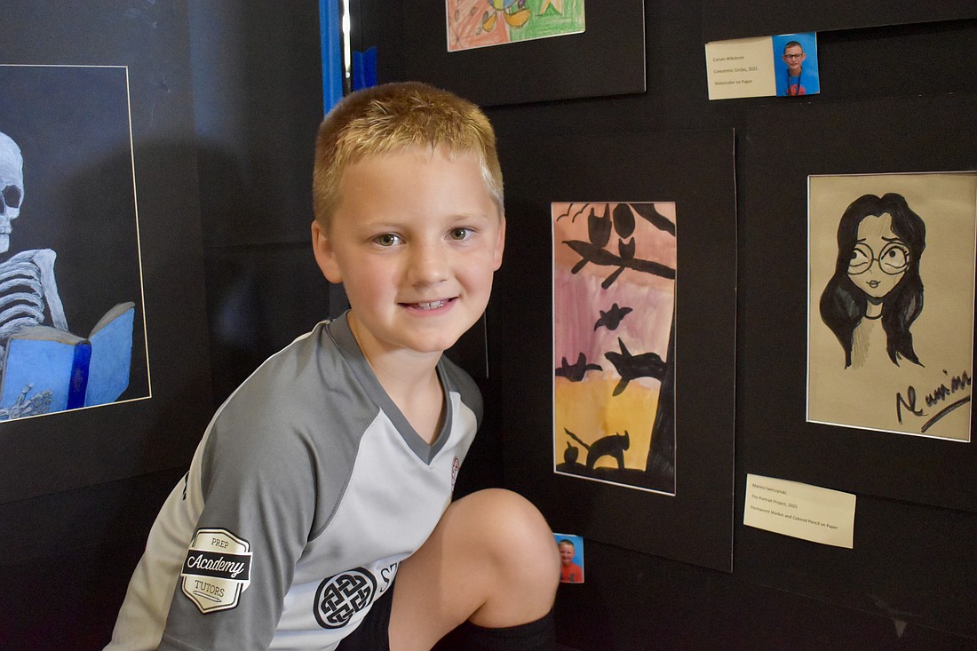 Evan Prince, a second grader at Freedom Elementary, poses next to his masterpiece, "Warm Colored Sky."