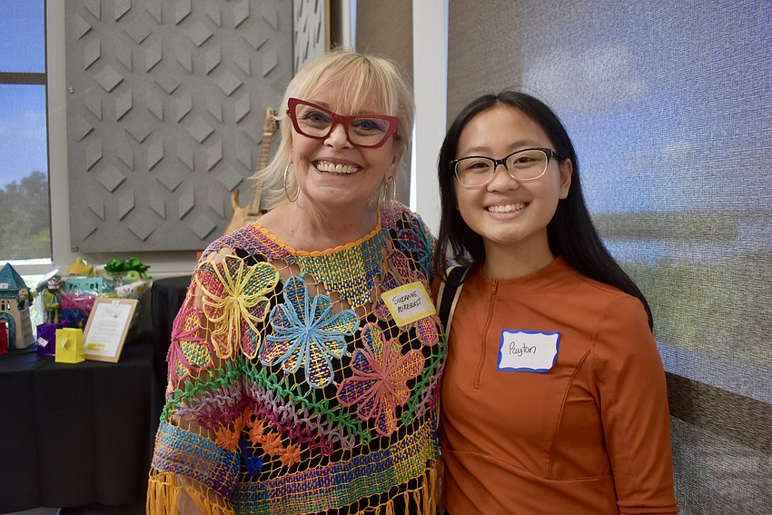 Suzanne Mireault and Payton Khang oversee the silent auction. Khang is a member of the Key Club at Palmetto High School and is volunteering for the day.
