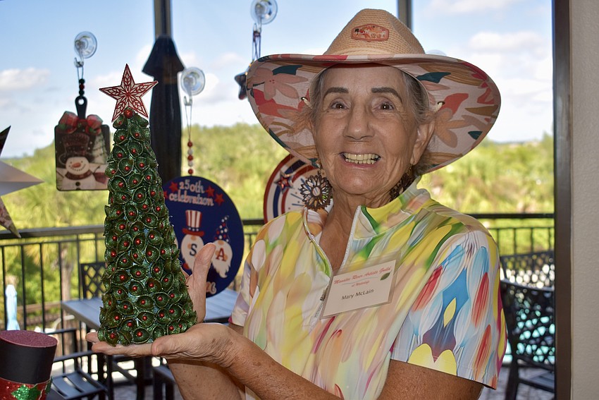 Mary McLain creates unique Christmas decor. The tree she's holding was made out of pasta shells.