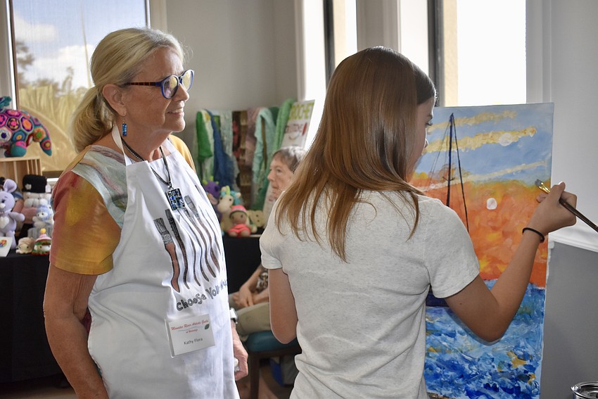 Kathy Fiora looks on as Aniston Brockway-Macek contributes to the group masterpiece.