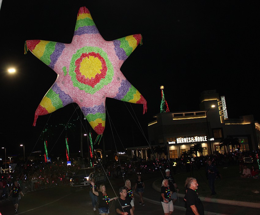Walkers from Rocco's Tacos pull a giant piñata along the Santa's Grand Arrival Parade route.