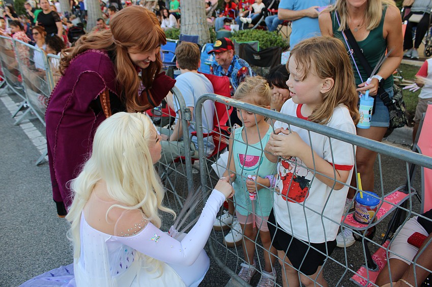 Sarasota's Lea Woreschek, 5, is a bit hesitant to reach out to the characters walking the parade route, but Raegan Papin, 7, is loving the moment with Elsa.