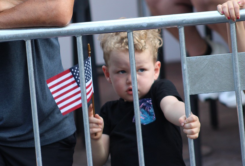 Lakewood Ranch 3-year-old Cash Quinteros, showing his patriotism, has to watch the Tribute to Heroes Parade from behind bars.