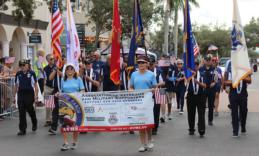 Del Webb's Kelly Naughton and Karen Nasello carry the banner for the Association of Veterans and Military Supporters during the Tribute to Heroes Parade in Lakewood Ranch.