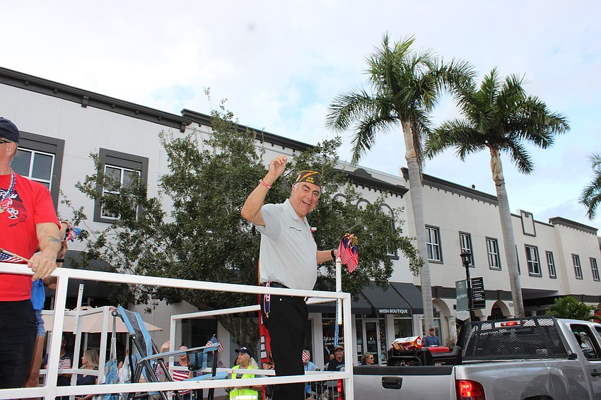 Del Webb's Herman Martinez, an Army Sergeant in Vietnam, throws little American flags to the crowd during the Tribute to Heroes Parade.