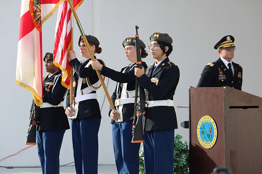 Sarasota High School Color Guard members Madisen Dwarika, Lindsey Nelson, Cyleigh Harrington and Camila Cavazos stand centerstage as Charles Mopps approaches the podium for Veterans Day.