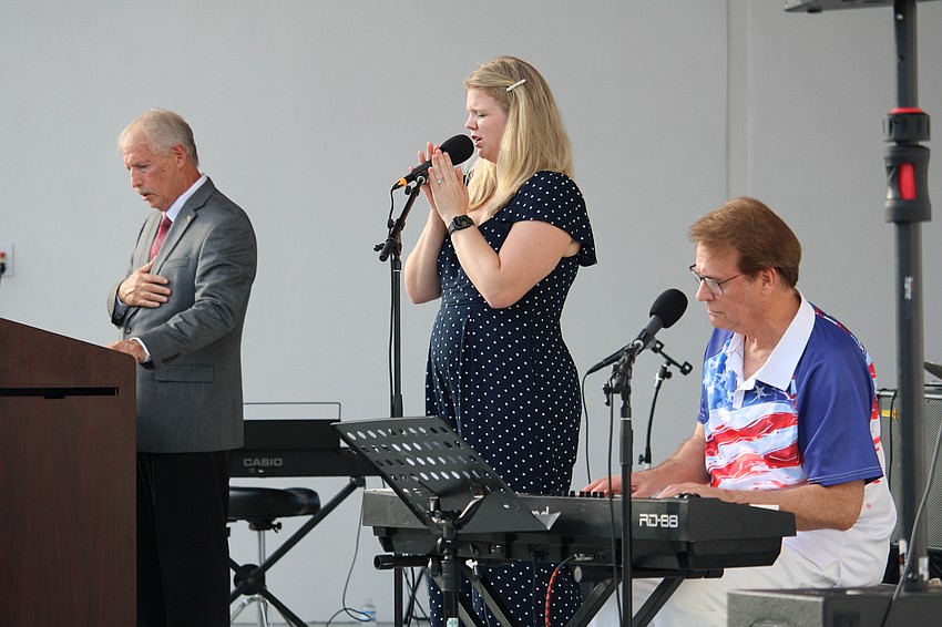 Town Manager Howard Tipton, Alyssa Adamson and Brian Gurl lead attendees in singing the national anthem ahead of Veterans Day on Nov. 8 at the Town Center Green.
