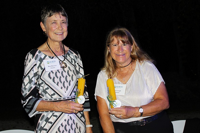 Big Waters Land Trust volunteers Marie Baumann and Carol Joseph demonstrate to Party in Paradise-goers how to craft a hand-rolled beeswax candle.