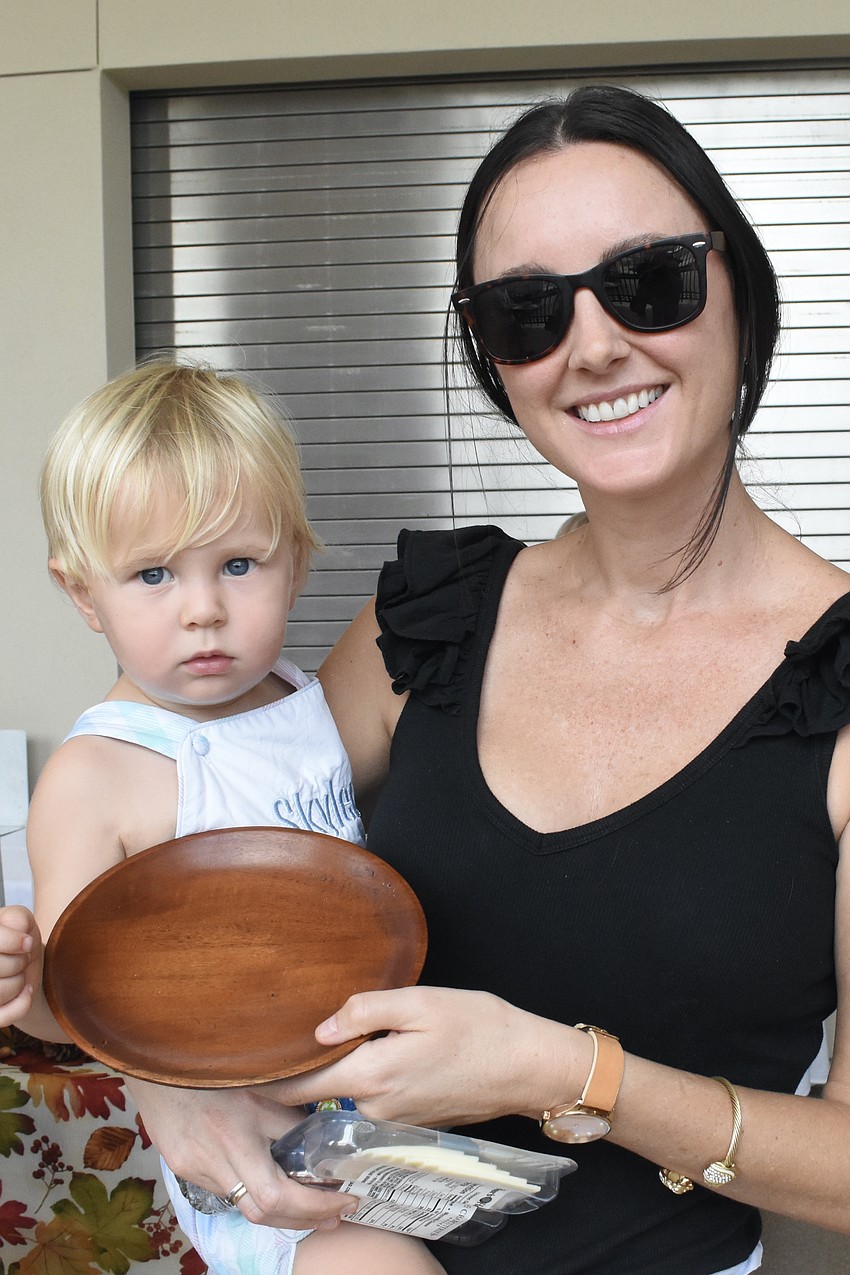 Alessi Keen and Skyler Keen, 1, carry a bowl as they walk through the event.