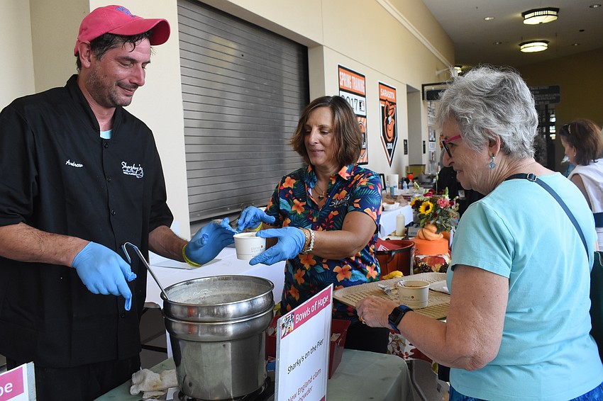 Andrew Mack and Patty Miller serve soup to Carole Gorin.