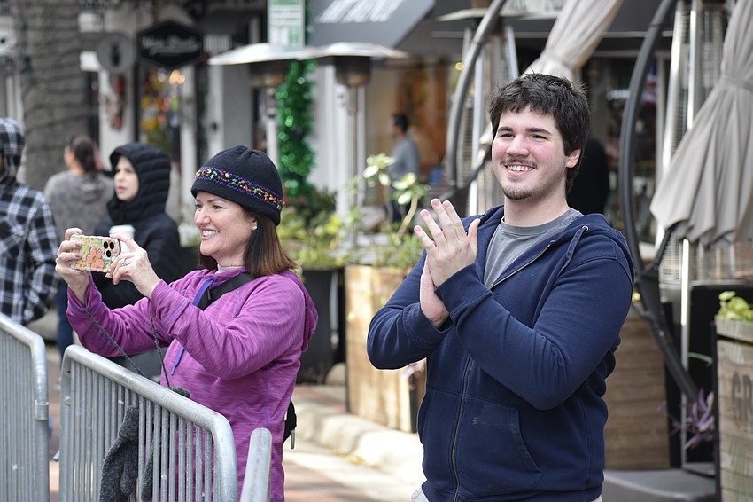Beth Mager and Donovan Schultz applaud as students from Sarasota High School walk by.