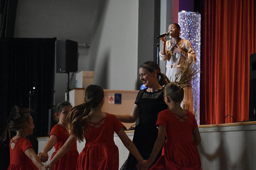 Elisha Byerly and Sarasota Contemporary Dance students dance at the front of the room, during a performance by vocalist Syesha Mercado.