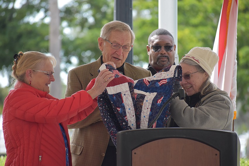 Tutti Kennedy (left) and Kathy Davidson, present a quilt to Mike Bennett, as Darrell Butler looks on.