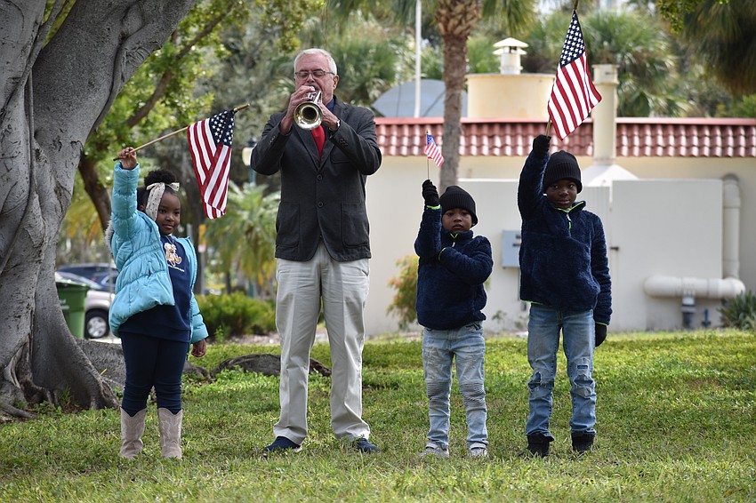 Taylin Saunders, 6, Danny Bilyeu, Caycen Ward, 6, and Carson Ward, 7, stand beside one another as Bilyeu plays Taps.