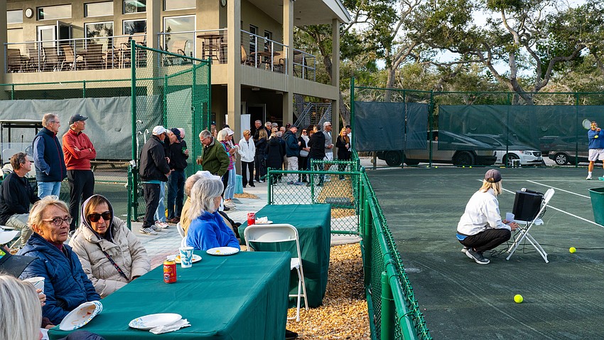 The crowd, players and organizers came to the Longboat Key Tennis Center dressed in long sleeves Tuesday, Nov. 11 for a meet and greet to welcome back seasonal residents. Tennis Center Manager Kay Thayer (crouched) and Friends of Tennis President Ron  Watts (red) watch on as a demo clinic is held.