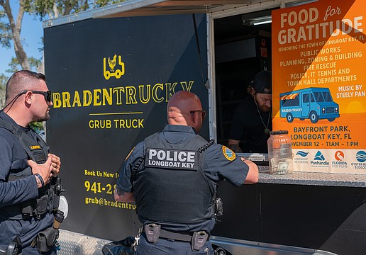 Longboat Key Police officer Mike Mathis gives his order to Brandon Clark while Sgt. Adam Montfort waits in line at Rotary Club of Longboat Key’s Food for Gratitude event where all town employees received free lunch to recognize their hard work after dual hurricanes in 2024.