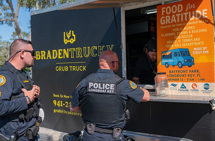 Longboat Key Police officer Mike Mathis gives his order to Brandon Clark while Sgt. Adam Montfort waits in line at Rotary Club of Longboat Key’s Food for Gratitude event where all town employees received free lunch to recognize their hard work after dual hurricanes in 2024.