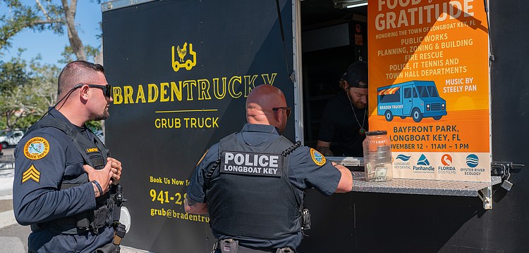 Longboat Key Police officer Mike Mathis gives his order to Brandon Clark while Sgt. Adam Montfort waits in line at Rotary Club of Longboat Key’s Food for Gratitude event where all town employees received free lunch to recognize their hard work after dual hurricanes in 2024.