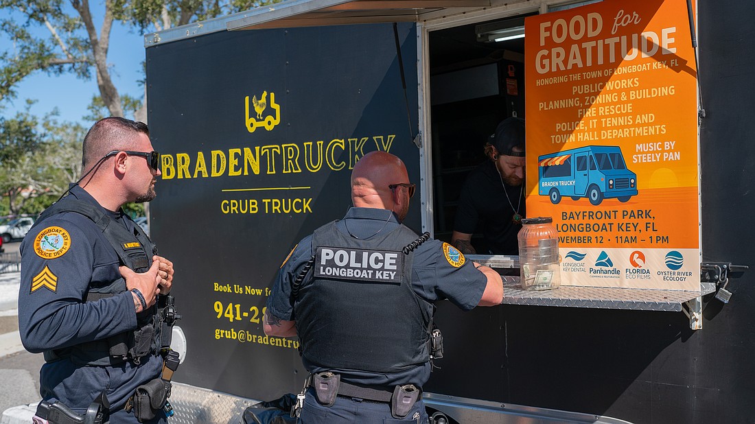 Longboat Key Police officer Mike Mathis gives his order to Brandon Clark while Sgt. Adam Montfort waits in line at Rotary Club of Longboat Key’s Food for Gratitude event where all town employees received free lunch to recognize their hard work after dual hurricanes in 2024.