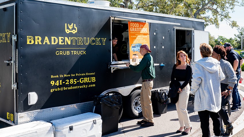 Bradentrucky Grub Truck’s Brandon Clark takes an order from a Town of Longboat Key employee as others chat in line at Rotary Club of Longboat Key’s Food for Gratitude event where all town employees received free lunch to recognize their hard work after dual hurricanes in 2024.